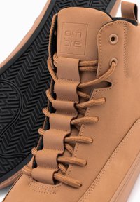 Žluté vysoké tenisky z hladké kůže, s texturovanými elastickými tkaničkami, gumovou podrážkou s herringbone vzorem a logem na jazyku.