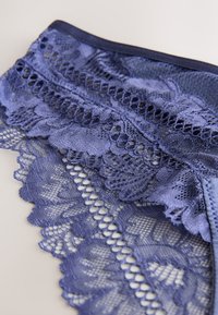 Biancheria intima in pizzo blu navy con intricati motivi floreali, bordi smerlati e una cintura testurizzata con un design a rete fine.