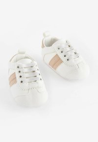 Zapatillas blancas para bebé fabricadas en material sintético con rayas beige, con un acabado texturizado, puntera redonda y cierre de cordones en la parte frontal.