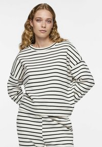 Sweatshirt rayé en crème avec des lignes horizontales noires, doté d'un col rond et d'une coupe décontractée, fabriqué en mélange de coton doux.