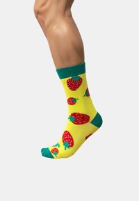 Calcetines amarillos con un patrón de fresas en rojo, con detalles verdes en el puño y la punta, hechos de un material suave y elástico.
