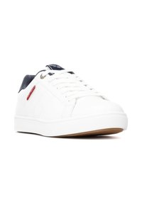 Zapatillas deportivas blancas con parte superior sintética suave, acentos en azul marino en el talón y una suela de goma con un agarre texturizado.