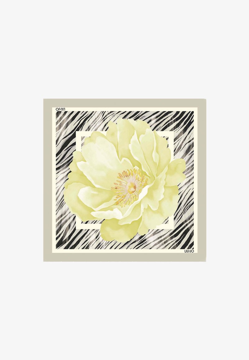 Grande fleur jaune pâle centrée sur un fond zébré noir et blanc avec une bordure beige et un cadre géométrique blanc.