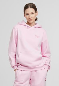 Rosa hettegenser med snorhette, frontlomme og to små hjerte-design i lys rosa, kombinert med matchende rosa joggebukser.