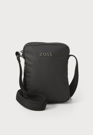 Bolso bandolera negro de nylon con forma rectangular, cierre de cremallera, correa ajustable y logotipo "BOSS" en relieve en la parte frontal.