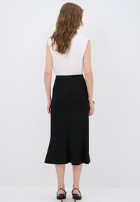 Musta, polvipituinen hame, jossa on istuva vyötärö ja levenevä helma. Yhdistetty valkoiseen hihattomaan paitaam. Sileä pinta ja minimalistinen muotoilu.