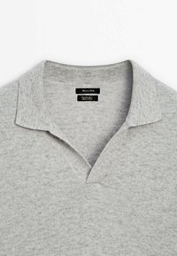 Grijze trui met een kraaghals en een v-vormige opening. Gemaakt van een zachte, textuurstof met subtiele vlekken in het gehele materiaal.