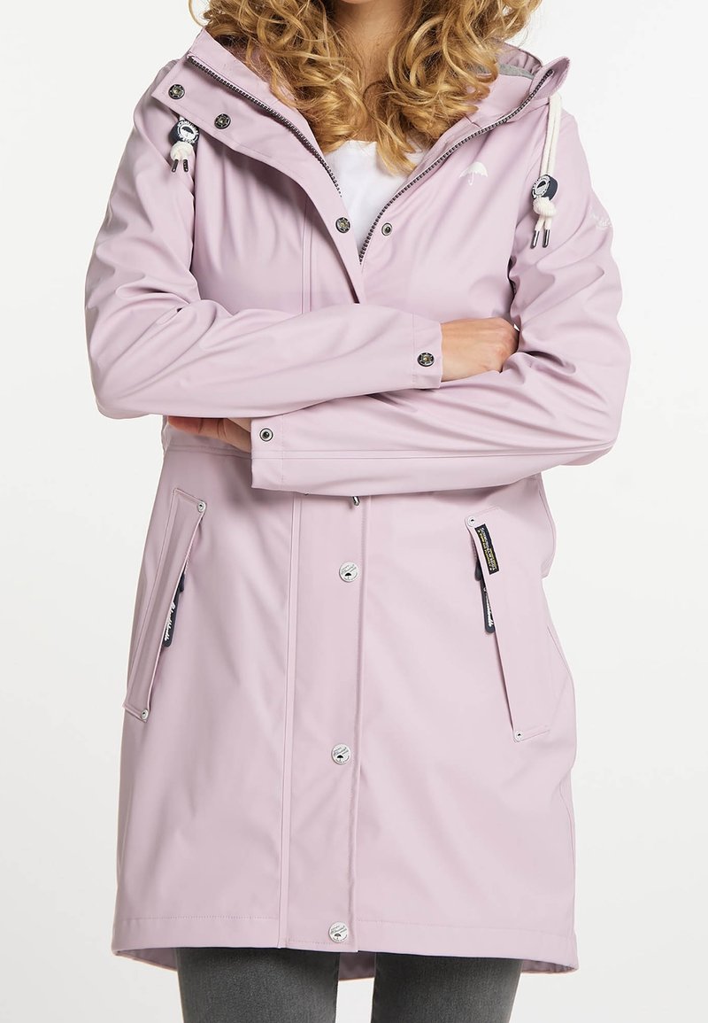 Ljusrosa regnjacka med huva, knappstängning, två sidofickor och en slät, vattenavvisande yta. Har en dekorativ dragrem.