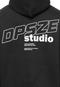 Sort hættetrøje med fed hvid tekst: "DPSZE studio," "HUSTLE SEASON," og "NEVER GIVE UP THE HUSTLE" med en glat, blød tekstur.