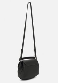 Sac noir à bandoulière en matériau texturé, présentant une forme arrondie, une sangle ajustable et une fermeture à rabat.