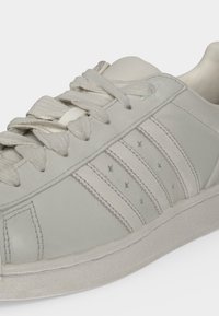 Λευκό δερμάτινο sneaker με υφασμένες κορδόνια, τριπλές ραμμένες ρίγες και οπές σε σχήμα αστεριού στο πλαϊνό πάνελ.