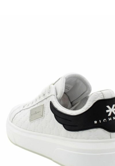 Sneaker bianca con materiale testurizzato, accentuazione nera con ali, placca con marchio argentato e suola bianca. Presenta lacci e collare imbottito.