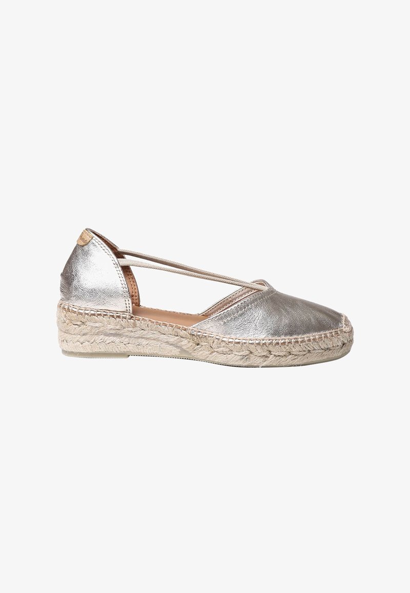 Metalické stříbrné espadrilky s plochou podrážkou z tkané juty a křížovými popruhy. Hladký povrch s kulatou špičkou a šitími detaily.