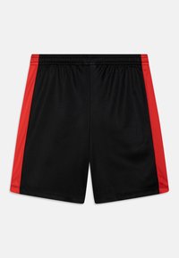 Pantalones cortos deportivos negros con paneles laterales rojos y cintura elástica, dispuestos sobre un fondo blanco.