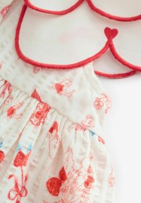 Balta kleita ar sarkaniem akcentiem, kam raksturīgas vēžveidīgas apkakles, forši raksti un savilkta tekstūra, izgatavota no mīksta, viegla auduma.