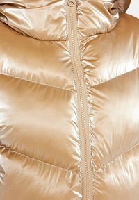 Giacca imbottita metallizzata dorata con chiusura a zip completa, texture trapuntata e cappuccio. I dettagli cuciti arricchiscono il design.