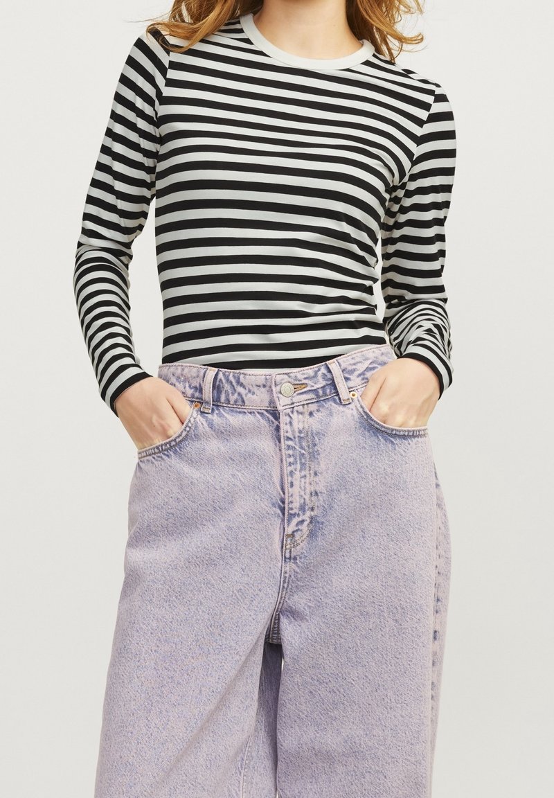 Haut à rayures noires et blanches à manches longues avec un col rond, associé à un jean en denim léger violet taille haute. Coupe décontractée et texturée.
