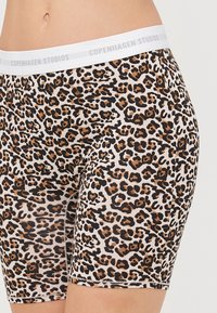 Lyonesklær som viser leopardmønster, laget av elastisk stoff med en hvit elastisk midje med "COPENHAGEN STUDIOS"-logo.