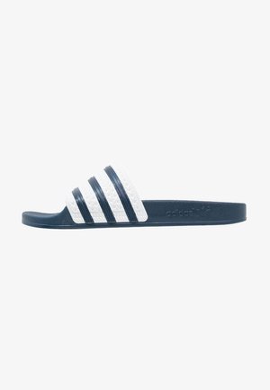 Mornarsko modra drsna sandal s teksturiranim belim trakom, ki ima tri temne črte. Trajen material z ravnim podplatom in poudarkom na logotipu.