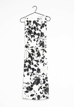 Weißes ärmelloses Midikleid mit schwarzem Blumenmuster und Taillengürtel, an einem schwarzen Kleiderbügel vor weißem Hintergrund hängend.