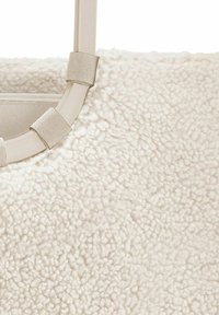 Borsa a spalla color crema con una superficie morbida e testurizzata. Presenta un manico rotondo in plastica fissato con strap in tessuto. Tasca interna con zip.