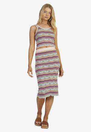 Gestreiftes Strick-Zweiteiler-Set mit einem cropped Top und einem figurbetonten Midi-Rock in Pastellfarben, mit einem gerippten Saum und Wellenmuster. Braune Slippers.