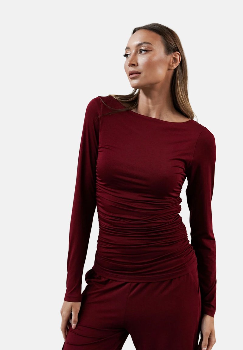 Burgundowa bluzka z długim rękawem, charakteryzująca się marszczonym wzorem z przodu, okrągłym dekoltem i dopasowanym krojem, w zestawie z pasującymi spodniami.