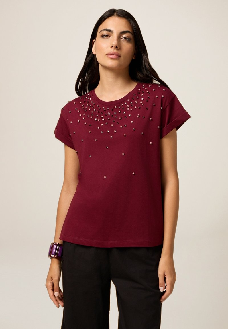 T-shirt en coton bordeaux à manches courtes, doté de clous en métal dispersés sur le devant, d'un col rond et d'une coupe ample.