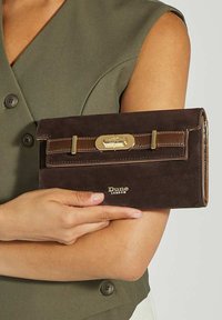 Brown suede wallet with a glossy brown trim, gold hardware, and a clasp closure. Features a logo embossed at the bottom.