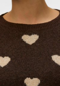 Hnědý pletený svetr se smetanovými vzory srdcí. Hladký kulatý výstřih a měkká textura, navržený pro uvolněný střih.