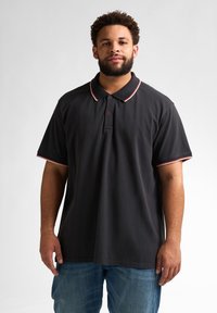 Czarna koszulka polo z krótkim rękawem, z kontrastującym czerwono-białym kołnierzykiem i wykończeniem rękawów w paski, z dwoma guzikami przy dekolcie i prostym dołem.