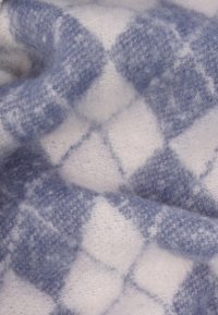 Μαλακό μάλλινο κουβερτάκι σε μπλε και λευκό, με μοτίβο διαμαντιού και αφράτη υφή, που παρουσιάζει εναλλασσόμενες ανοιχτές και σκούρες αποχρώσεις.