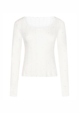 Witte longsleeve met geribbelde textuur, voorzien van verspreide kleine roze hartaccenten en een gegolfde halslijn.