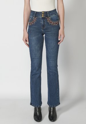 Blue denim jeans with a high waist, embellished pockets featuring colorful embroidery, and gold hardware. Fitted design, straight-leg cut.