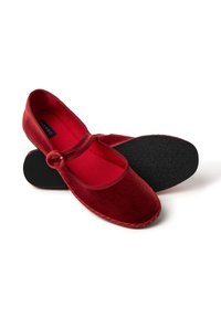 Rode fluwelen ballet flats met een ronde neus, elastische band en getextureerde zwarte buitenzool. Binnenvoering in contrasterend rood. Subtiele stikseldetails.