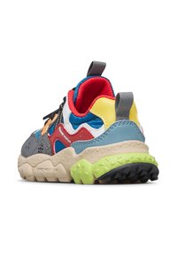 Sneaker da escursionismo multicolore con suola spessa, collo imbottito rosso, pannelli blu, gialli, rossi e grigi, e suola esterna nera con texture.