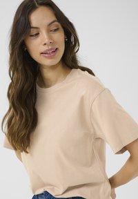 Lys beige t-shirt lavet af blød bomuld, med en afslappet pasform og korte ærmer, samt en simpel rund halsudskæring. Minimalistisk design.