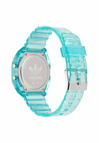 Montre numérique transparente turquoise avec un cadran octogonal massif, un dos en acier inoxydable et un bracelet relié présentant des motifs découpés.