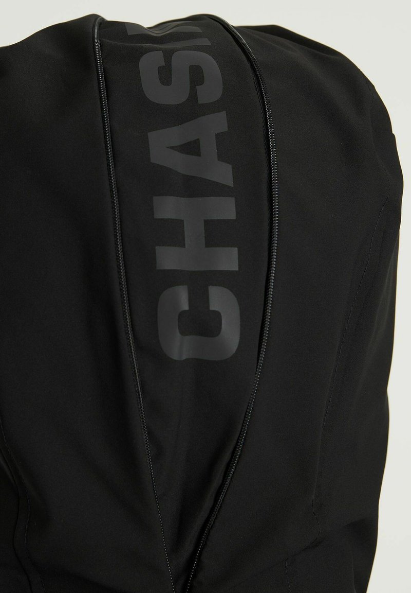Czarna kurtka z wyraźnym pionowym zamkiem i odważnym napisem "CHASER" z tyłu wykonana z gładkiego, matowego materiału.