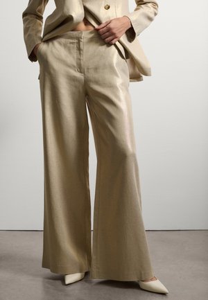 Pantaloni beige a gamba larga su misura realizzati in un tessuto leggero e strutturato. Presentano una parte frontale piatta, tasche laterali e una leggera lucentezza.