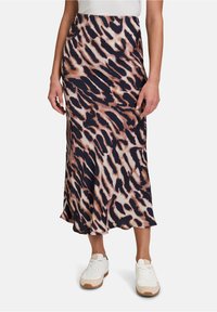 Jupe midi à imprimé léopard dans des tons marine, crème et pêche, fabriquée à partir d'un tissu doux et texturé avec une drapé délicat. Détail de fente latérale visible.