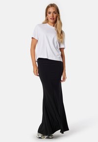 Witte T-shirt met korte mouwen, gecombineerd met een zwarte, jurk lengte, strakke rok. De stof lijkt glad en rekbaar, geschikt voor casual draag.