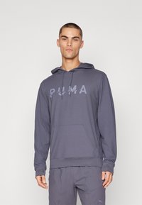 Grauer Hoodie mit Kängurutasche, großem Logo auf der Vorderseite, Kapuze mit Kordelzug und gerippten Bündchen. Glatte Textur, athletische Passform.
