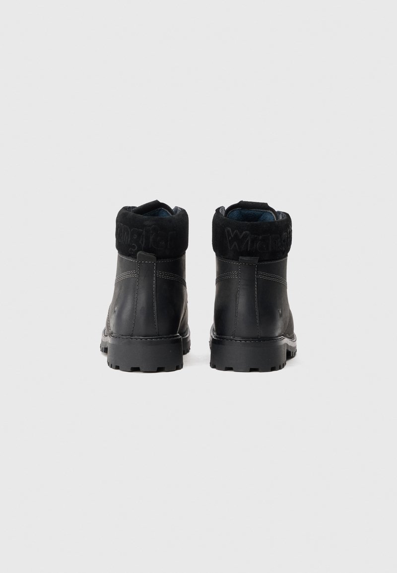 Botas negras hasta el tobillo con parte superior de cuero y cuello de ante. Presenta detalles de costura y una suela de goma texturizada para mayor tracción.