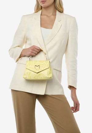 Bolso de mano con estampado de serpiente amarillo y forma estructurada, con un cierre de metal y un asa corta, combinado con un blazer crema y pantalones beige.