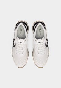 Baskets blanches en cuir perforé avec logo "MK" noir sur les côtés et la languette, semelles intérieures estampillées "Michael Kors", vues de dessus.