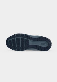 Σκούρα μπλε εξωτερική σόλα αθλητικού Nike με ανάγλυφο σχέδιο πέλματος, βαθιές αυλακώσεις και ορατό λογότυπο "NIKE" στη δεξιά πλευρά, σε λευκό φόντο.