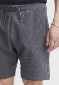 Gray textured shorts with a waffle pattern, featuring a drawstring waist, side pockets, and slightly rolled hem.