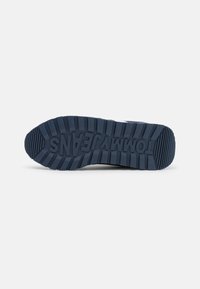 Suola di sneaker blu navy con una superficie in gomma testurizzata caratterizzata da profonde scanalature e marchio in rilievo. Progettata per la trazione e la durata.