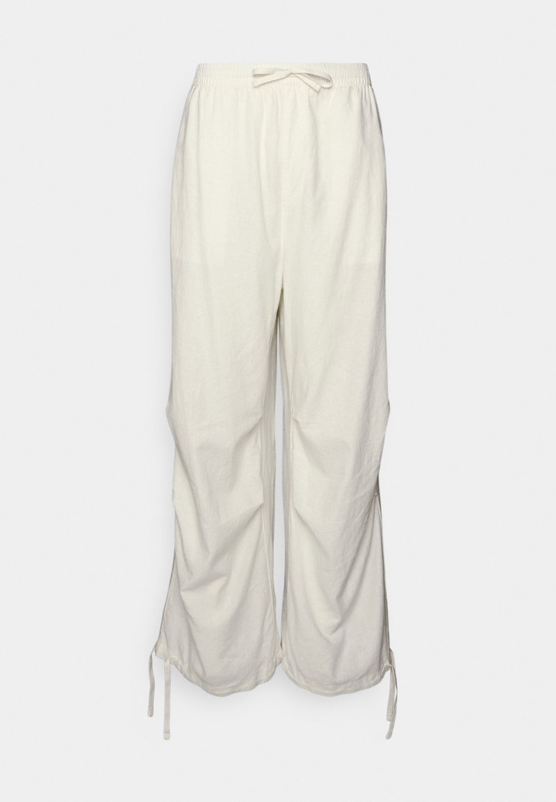 Pantalon blanc ample en coton avec taille élastique et cordons à la taille et jambes larges sur fond clair.